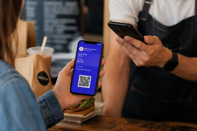 Carte de fidélité à tampons dans Apple Wallet, présentée sur un iPhone au comptoir d'un glacier et scannée par le commerçant