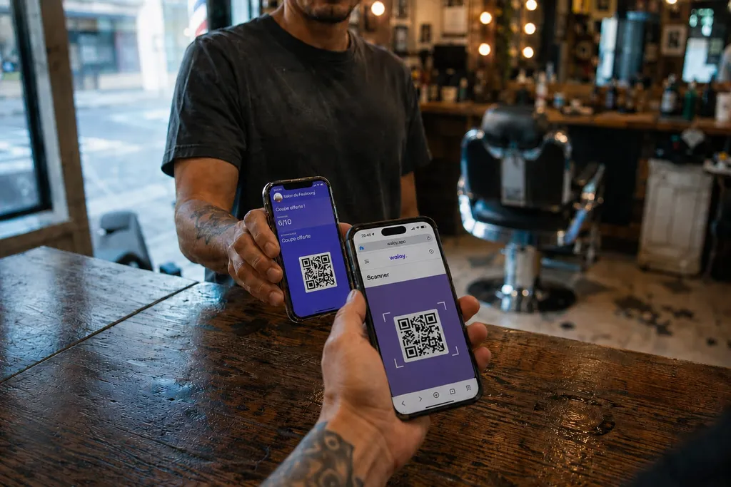 Barbier scannant avec son téléphone la carte de fidélité d'un client affichée dans Apple Wallet, récompense « coupe offerte », au comptoir d'un salon