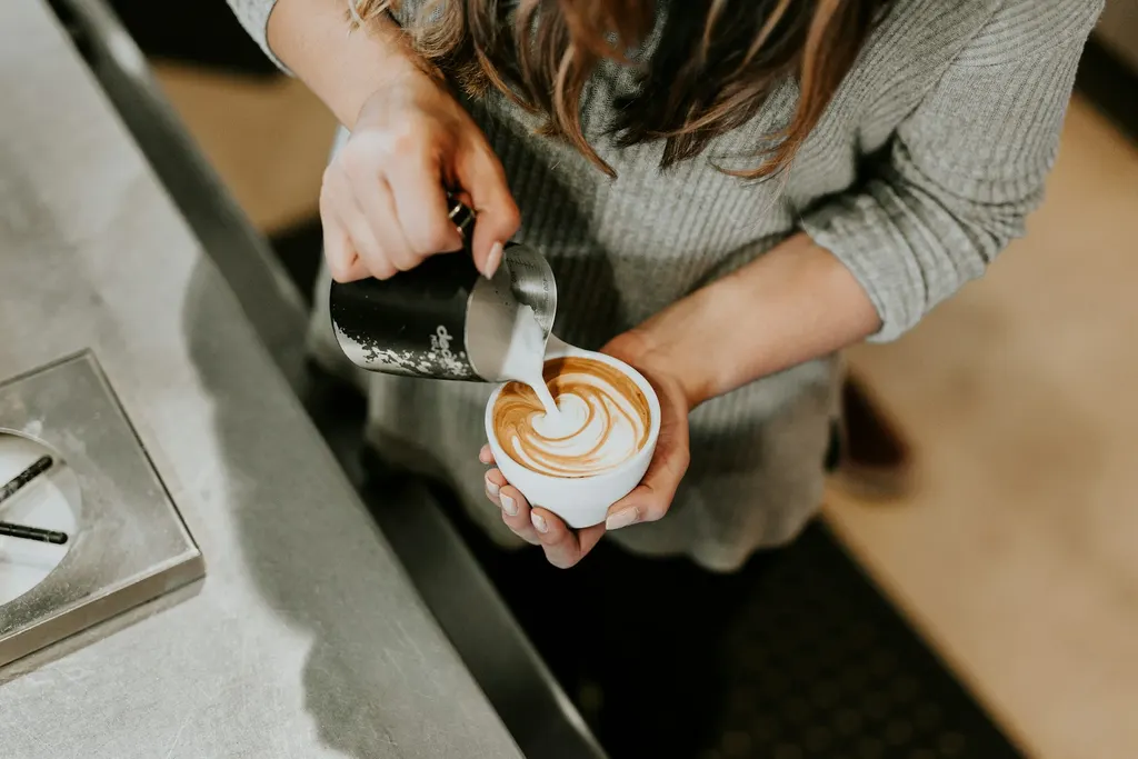 Barista versant le lait dans un cappuccino au comptoir d'un café